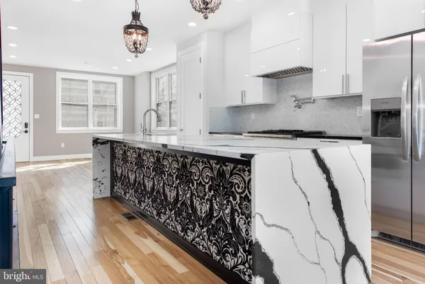 a kitchen with stainless steel appliances granite countertop a refrigerator a sink dishwasher a stove and a dining table with wooden floor