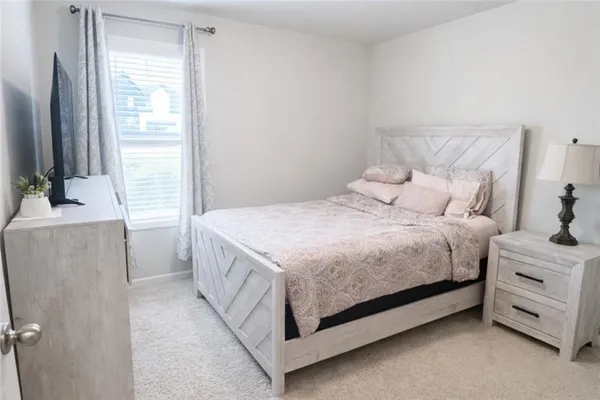 a bedroom with a bed and a flat tv screen on dresser