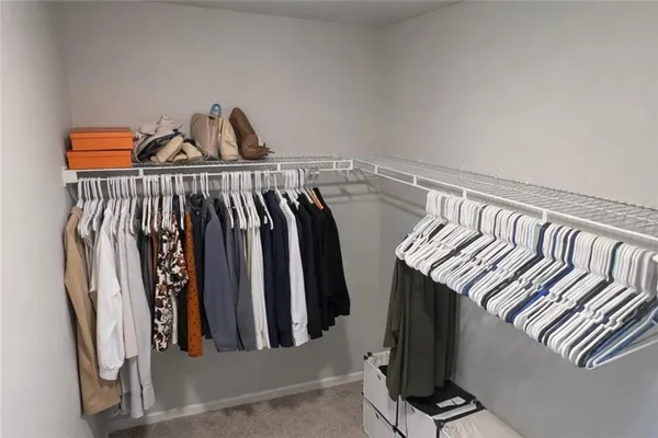 a view of walk in closet with clothes and shoes