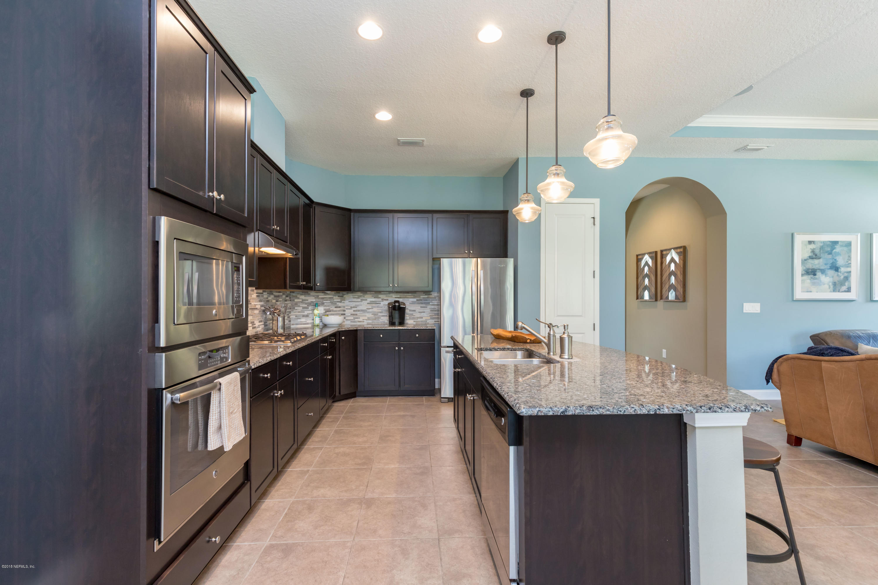 3811 Valverde Circle Jacksonville, FL 32224 - Photo 17 of 42 a kitchen with stainless steel appliances kitchen island granite countertop a refrigerator a sink dishwasher a stove and a dining table with wooden floor