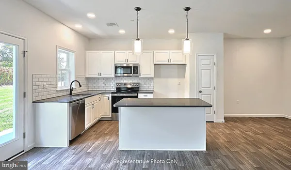 a kitchen with stainless steel appliances granite countertop a sink a stove a refrigerator and white cabinets with wooden floor