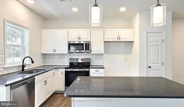 a kitchen with kitchen island granite countertop a sink a counter space appliances and cabinets