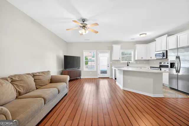 a living room with stainless steel appliances furniture and a kitchen view