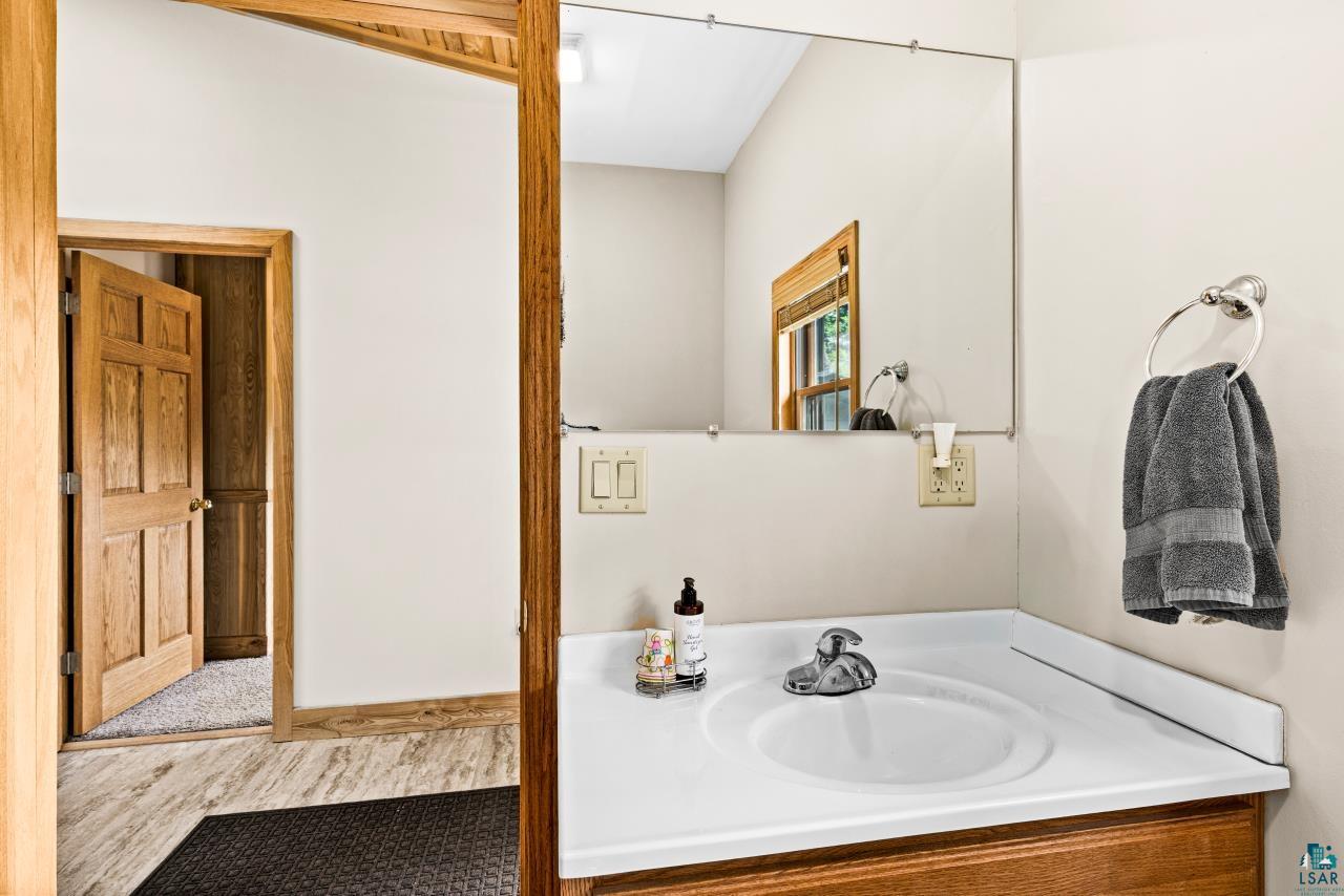4800 Tower Road Moose Lake, MN 55767 - Photo 56 of 83 Bathroom vanity with a polished chrome faucet, white countertop, and wood-finish cabinetry