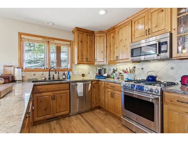 a kitchen with a refrigerator a sink and dishwasher with wooden floor