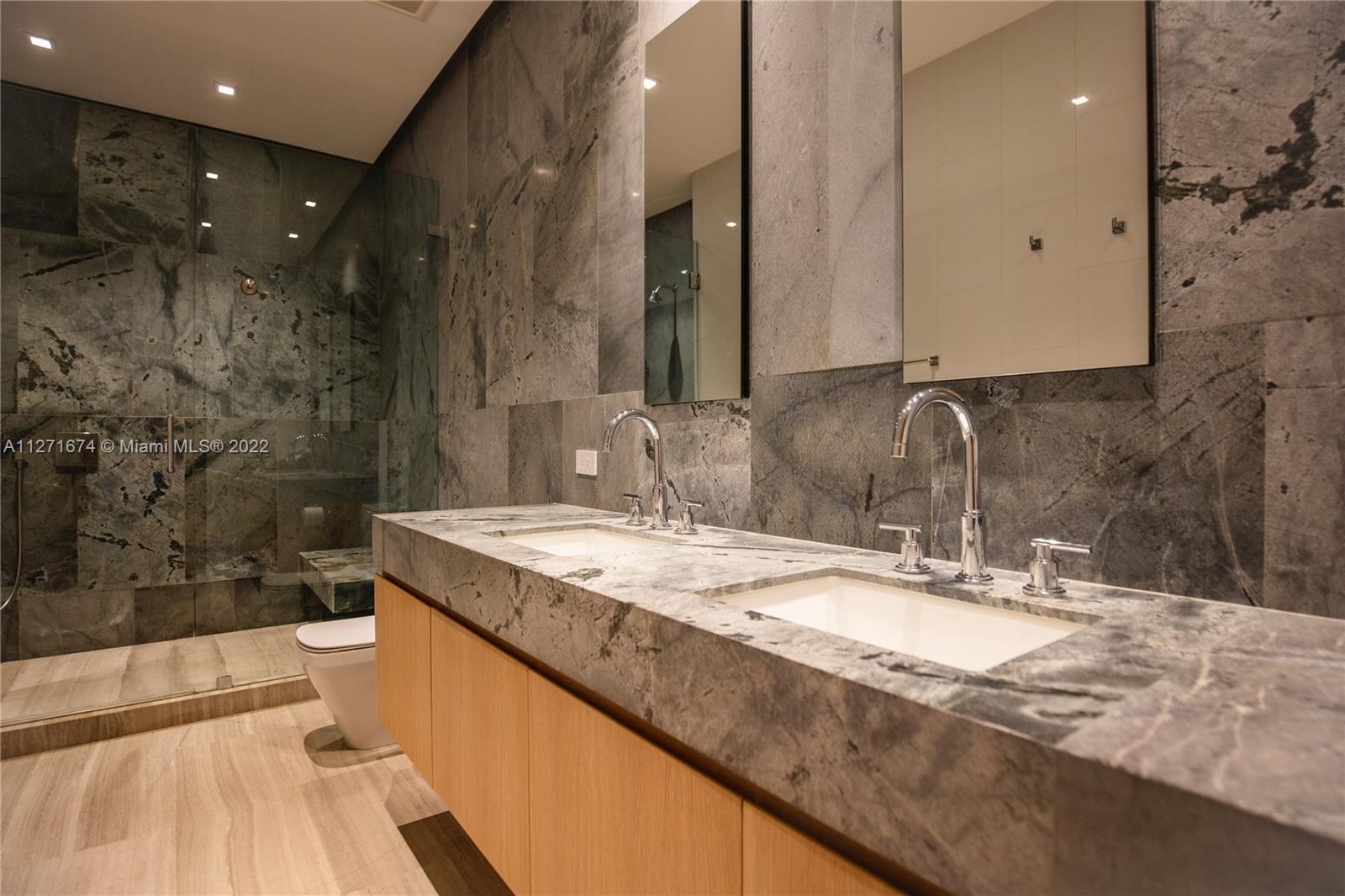 5061 North Bay Road Miami Beach, FL 33140 - Photo 16 of 23 a bathroom with a granite countertop sink a toilet a mirror and bathtub