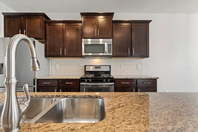 a kitchen with stainless steel appliances granite countertop a stove a sink and a microwave