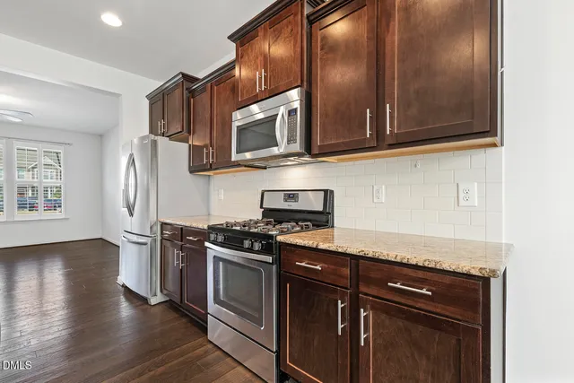 a kitchen with stainless steel appliances granite countertop a stove a sink and a microwave