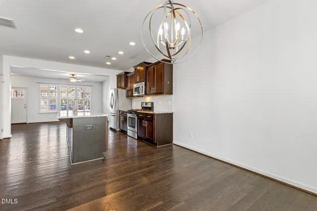 an open kitchen with wooden floor and stainless steel appliances