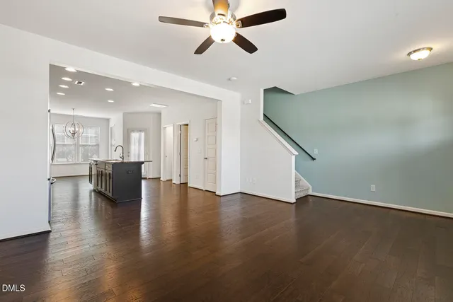 a view of an empty room with wooden floor and a ceiling fan