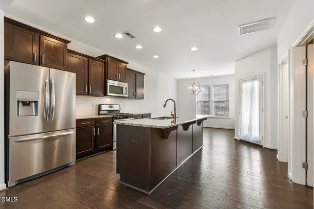 a kitchen with stainless steel appliances granite countertop a refrigerator a sink dishwasher a stove and a refrigerator with wooden floor