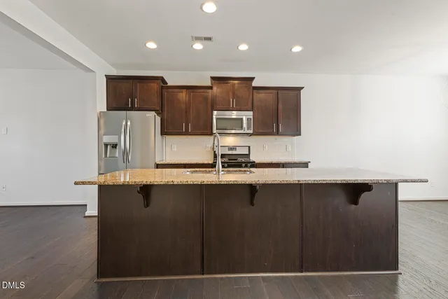 a kitchen with stainless steel appliances granite countertop a sink and a refrigerator
