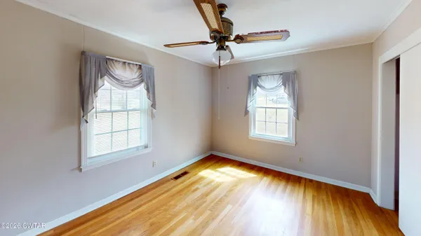 a view of empty room with wooden floor and fan