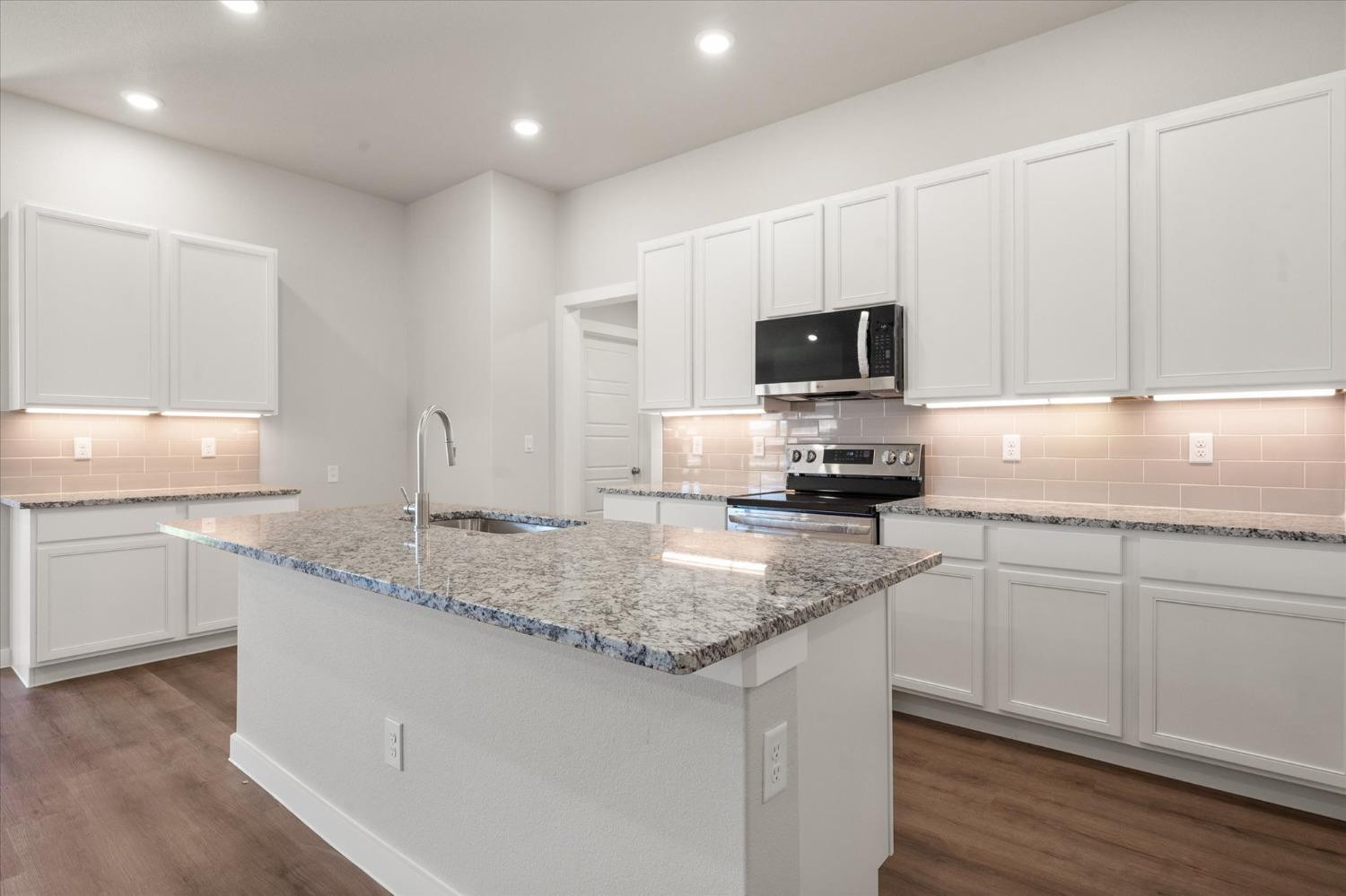 7007 9th Street Lubbock, TX 79416 - Photo 9 of 22 a kitchen with granite countertop a sink and a stove top oven