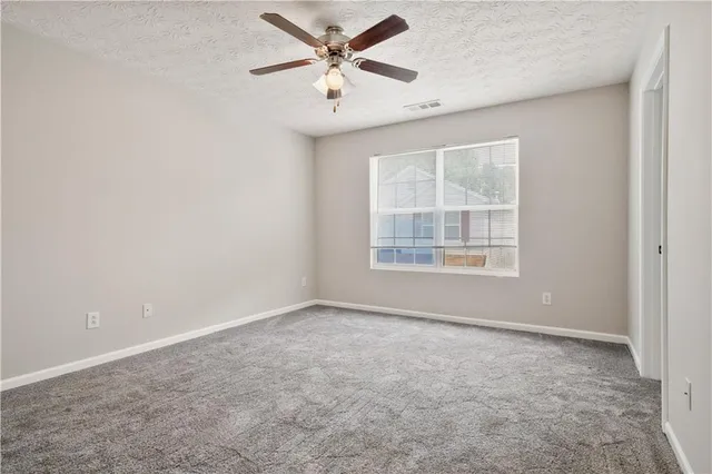 an empty room with windows and fan