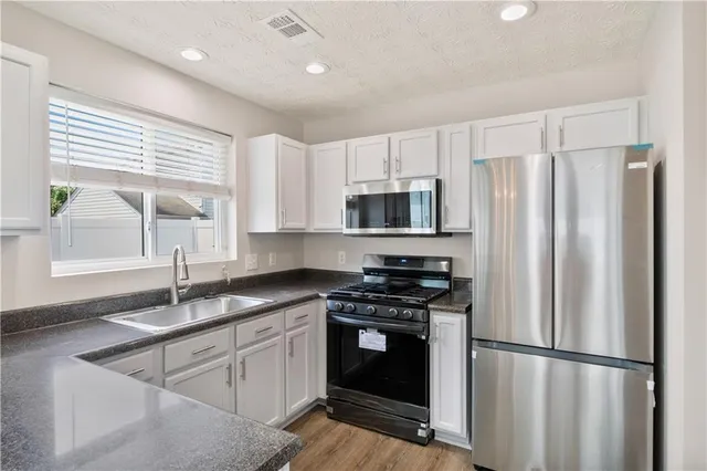 a kitchen with granite countertop a sink stainless steel appliances and window