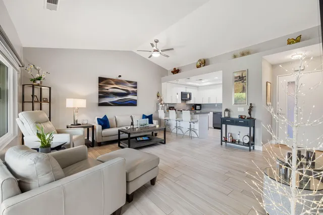a living room with furniture kitchen view and a wooden floor