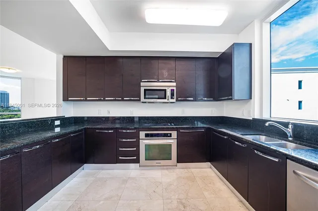 a kitchen with stainless steel appliances granite countertop a stove a sink and a microwave
