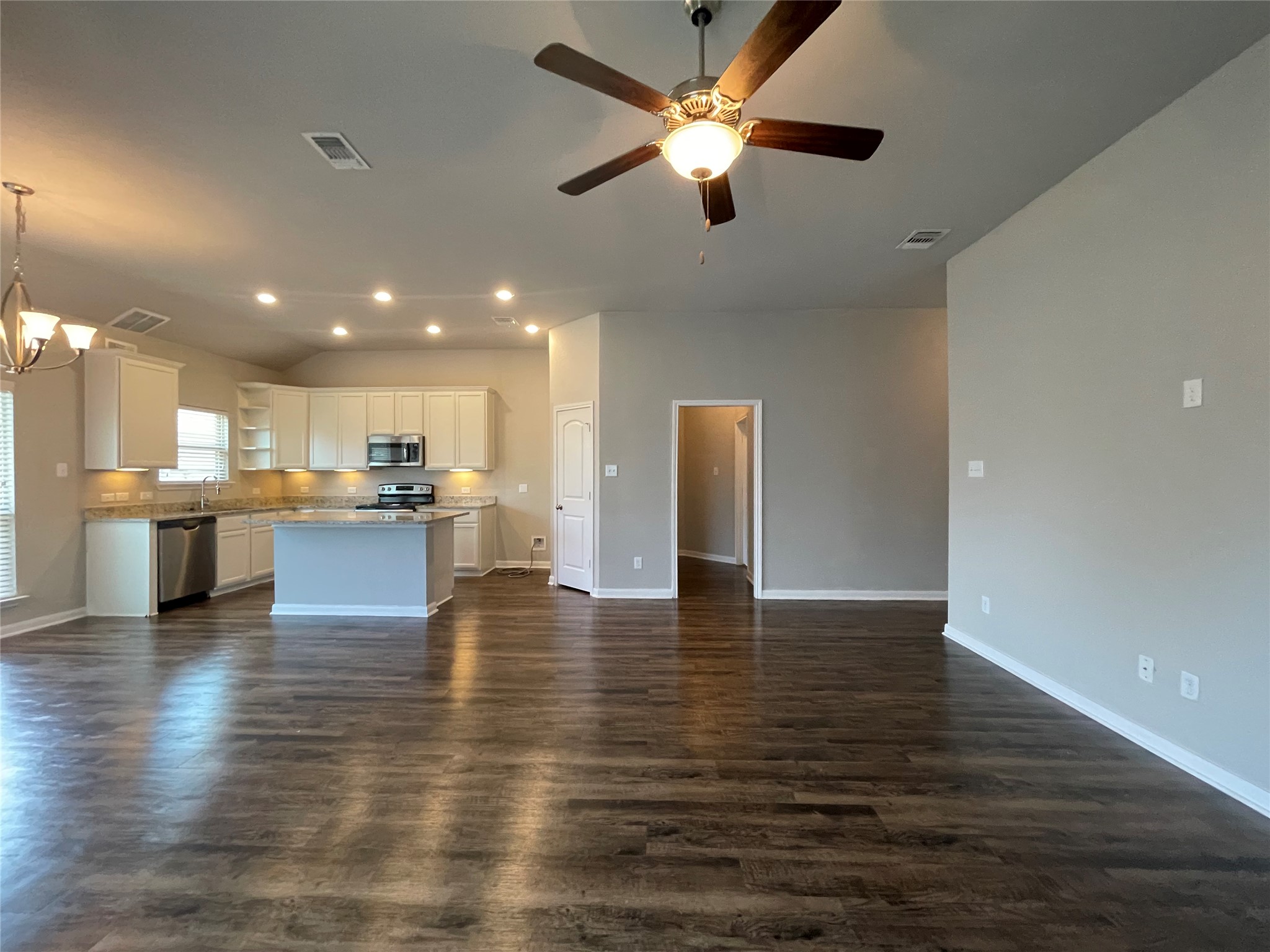 8113 Northgate Loop Temple, TX 76502 - Photo 9 of 35 Expansive open-concept living area featuring wood-finish flooring, a ceiling fan with integrated lighting, and a kitchen with white cabinetry, stainless steel appliances, and a central island