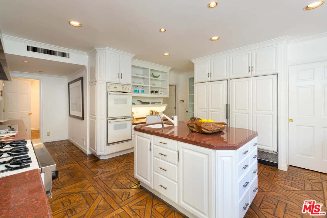 1027 Summit Drive Beverly Hills, CA 90210 - Photo 11 of 23 a kitchen with stainless steel appliances a stove a refrigerator and white cabinets