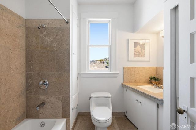 a bathroom with a granite countertop sink a toilet and shower