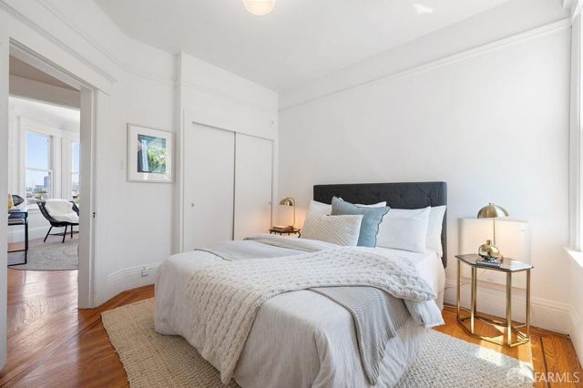 a spacious bedroom with a bed and wooden floor