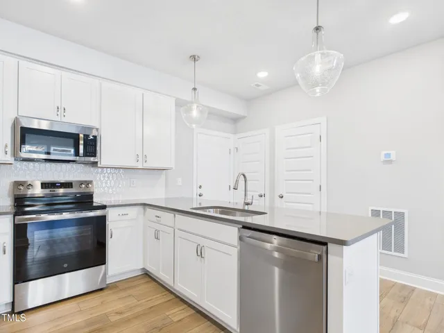 a kitchen with stainless steel appliances granite countertop a sink a stove and a wooden floors