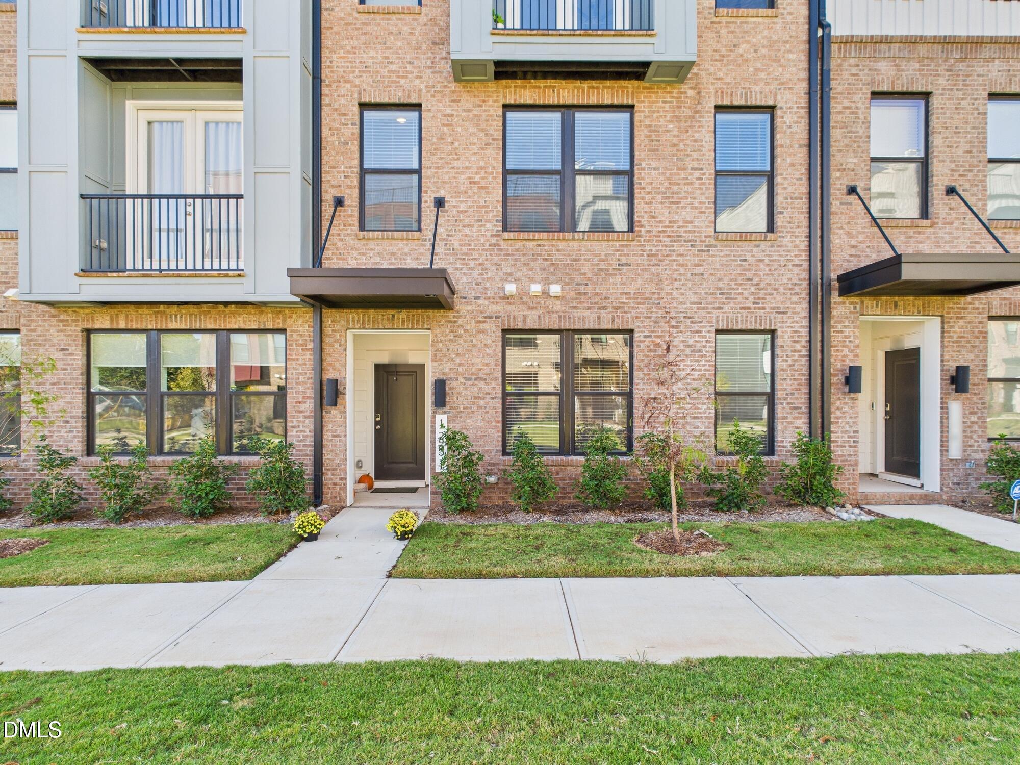 1251 Shaw View Alley, Unit 101 Raleigh, NC 27601 - Photo 2 of 47 a front view of a brick house with a yard and plants
