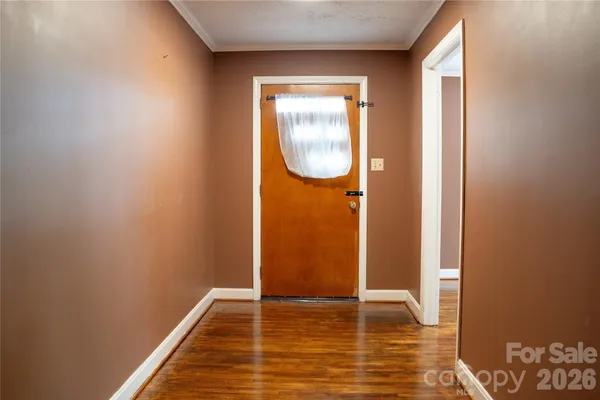 an empty room with wooden floor a fireplace a ceiling fan and kitchen view
