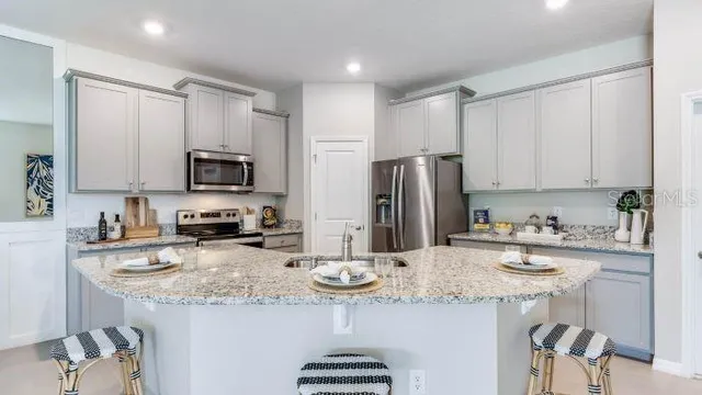 a kitchen with granite countertop a sink stainless steel appliances and white cabinets
