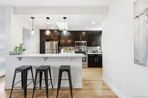 a kitchen with stainless steel appliances a sink a stove a refrigerator cabinets and a dining table