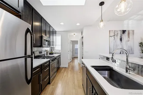 a kitchen with stainless steel appliances granite countertop a sink a stove and refrigerator