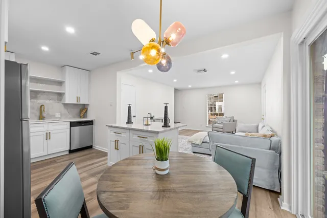a kitchen with a dining table cabinets stainless steel appliances and a chandelier