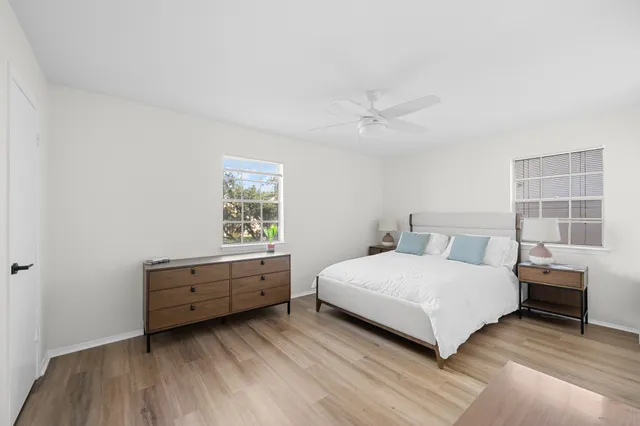 an empty room with wooden floor ceiling fan and windows