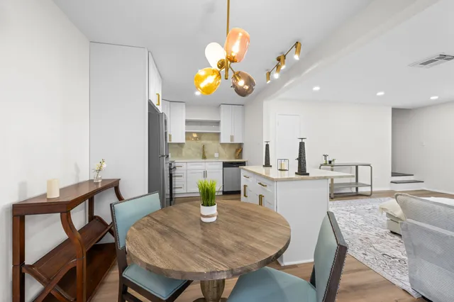 a kitchen with a dining table chairs sink and cabinets