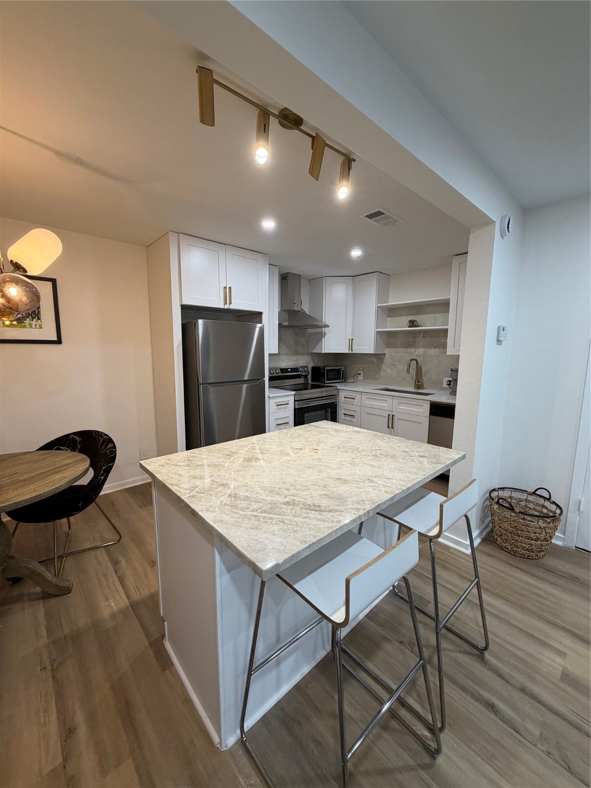 2012 Brun Street, Unit A Houston, TX 77019 - Photo 6 of 16 a kitchen with stainless steel appliances kitchen island a table chairs in it and wooden floors
