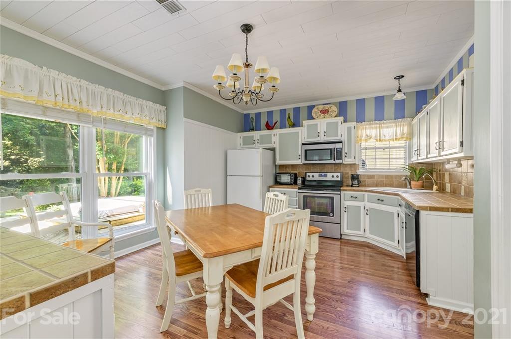 7335 Reedy Creek Road, Unit 25 Charlotte, NC 28215 - Photo 8 of 28 a kitchen with stainless steel appliances granite countertop a stove top oven a refrigerator a sink dishwasher and a dining table with wooden floor