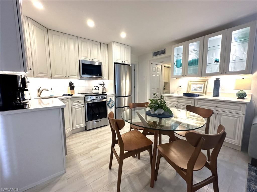 175 5th Avenue South, Unit 103 Naples, FL 34102 - Photo 2 of 18 a kitchen with stainless steel appliances granite countertop a stove a sink a refrigerator a kitchen island and chairs