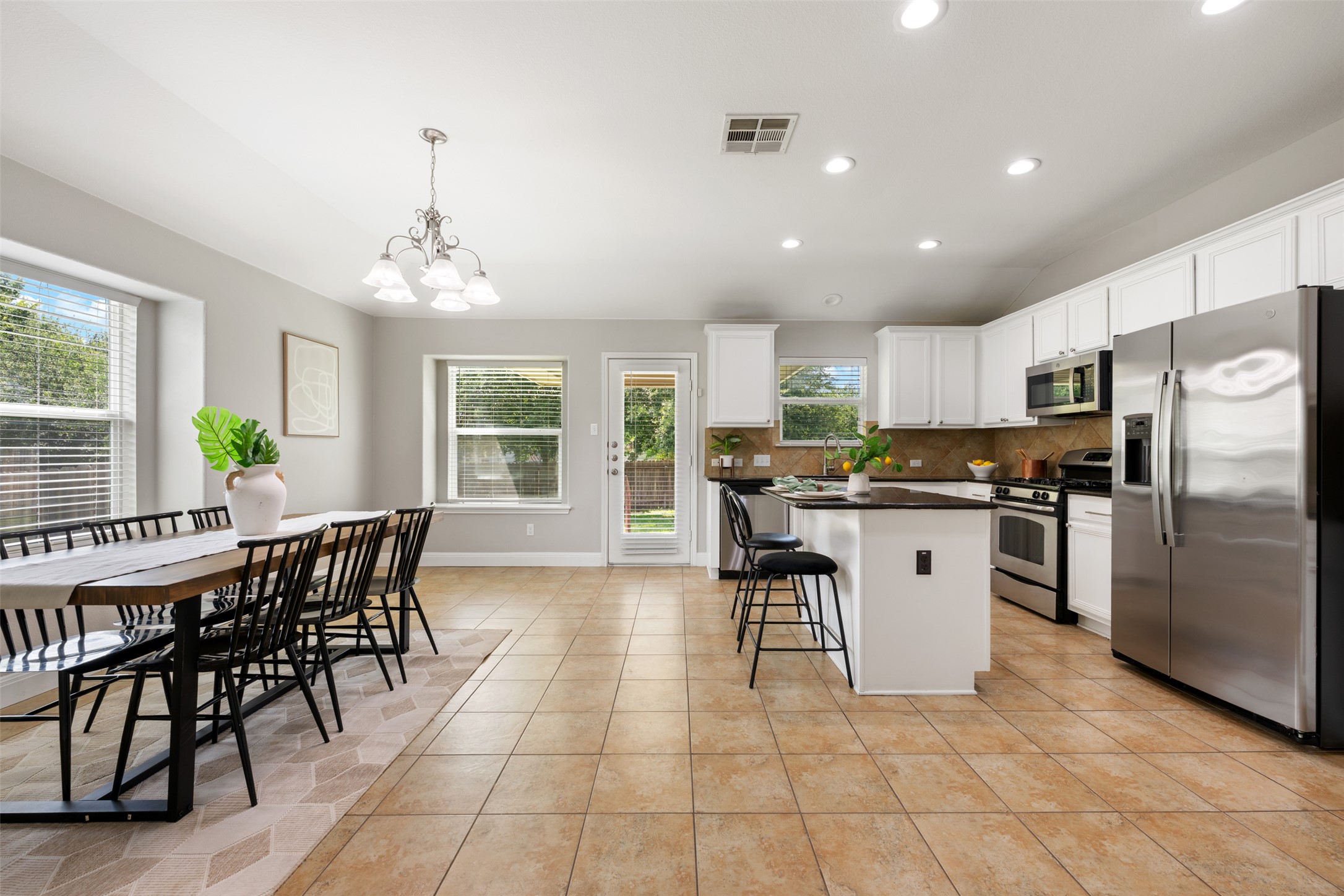 18820 Edinburgh Castle Road Pflugerville, TX 78660 - Photo 22 of 37 a open kitchen with stainless steel appliances granite countertop a stove top oven a sink a dining table and chairs