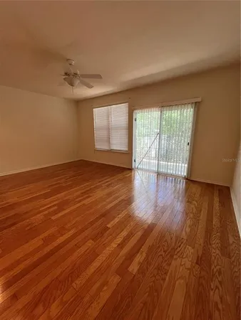 a view of an empty room with wooden floor and a window