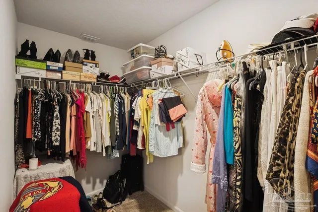 a view of walk in closet with clothes and shoes