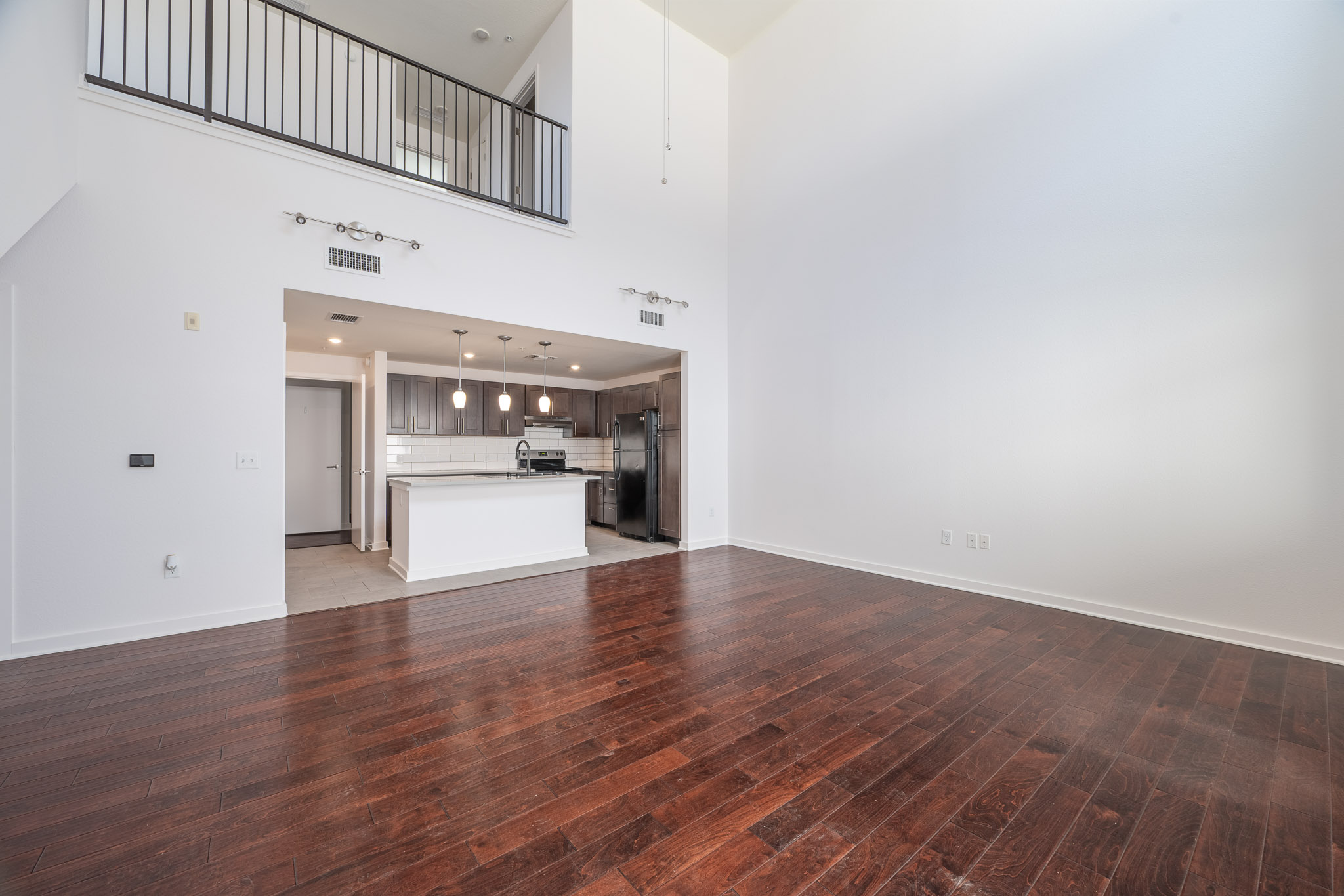 Unfurnished living room featuring a high ceiling and dark wood-style floors