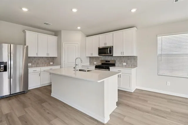a kitchen with cabinets stainless steel appliances a sink and a window