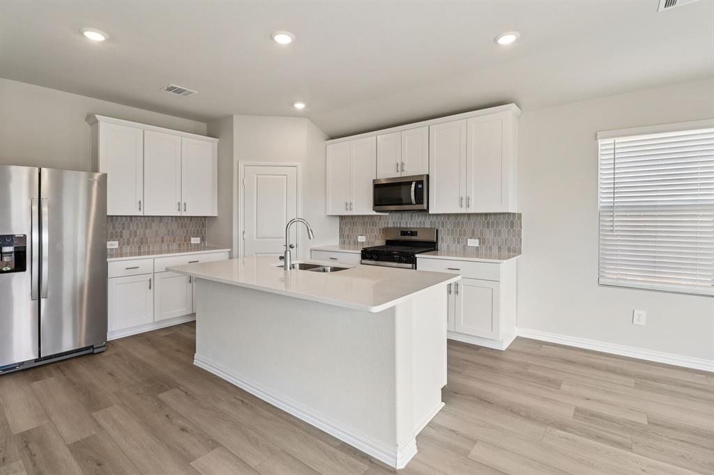 a kitchen with cabinets stainless steel appliances a sink and a window