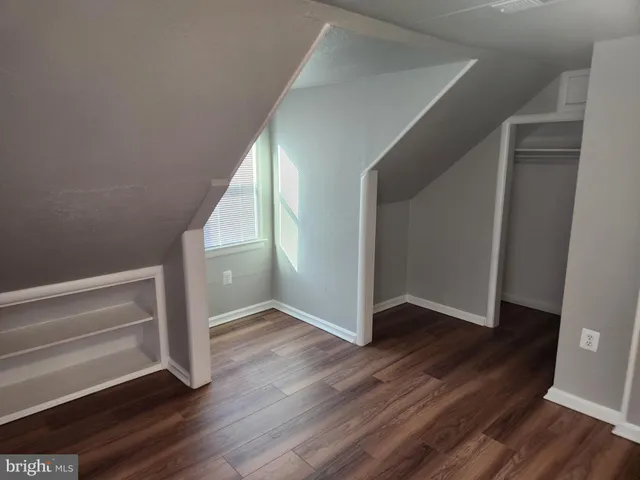 a view of an empty room with wooden floor and stairs