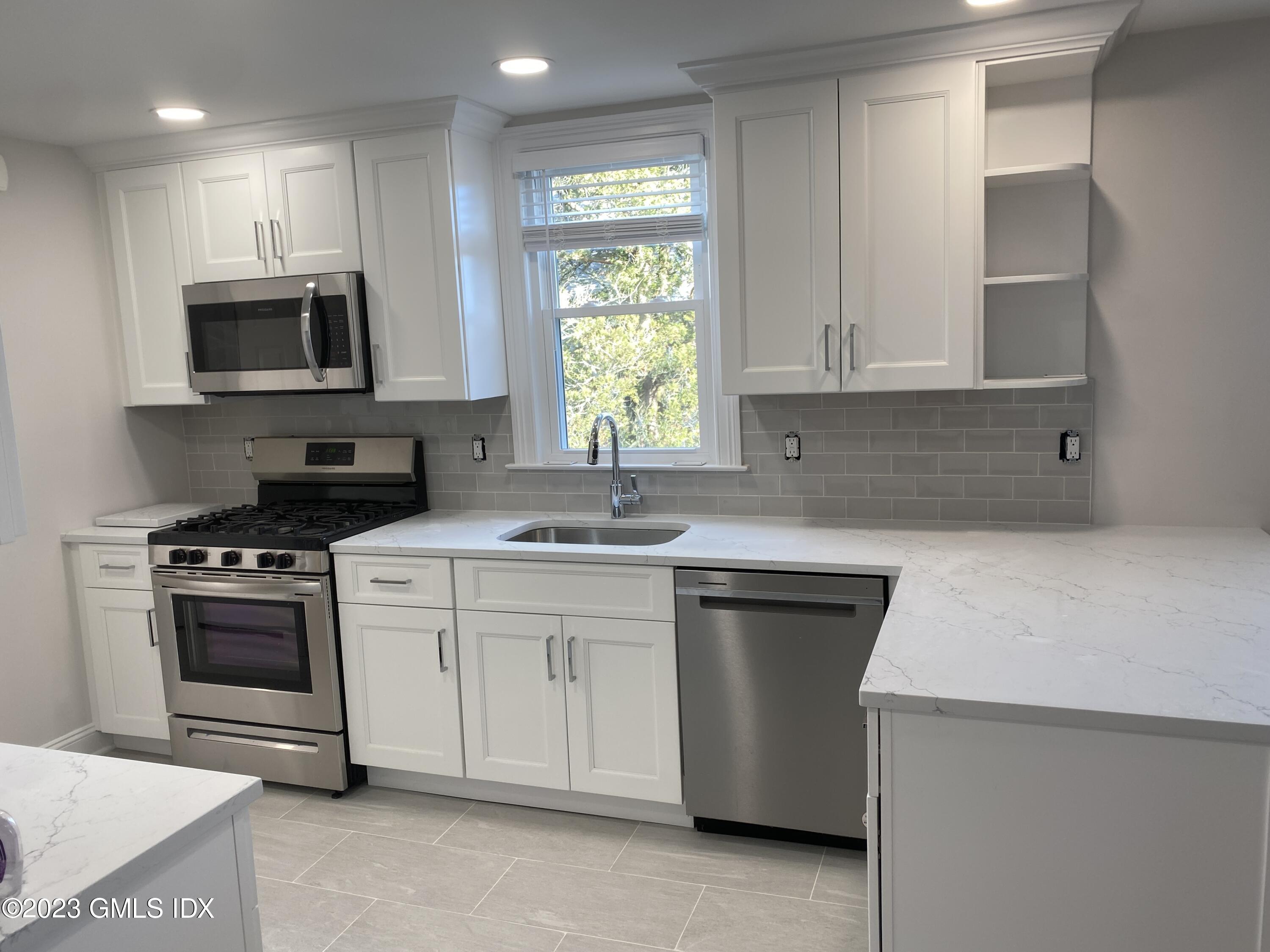 11 Old Field Point Road, Unit 2A Greenwich, CT 06830 - Photo 2 of 12 a kitchen with stainless steel appliances granite countertop a sink a stove a microwave a refrigerator a counter space and cabinets