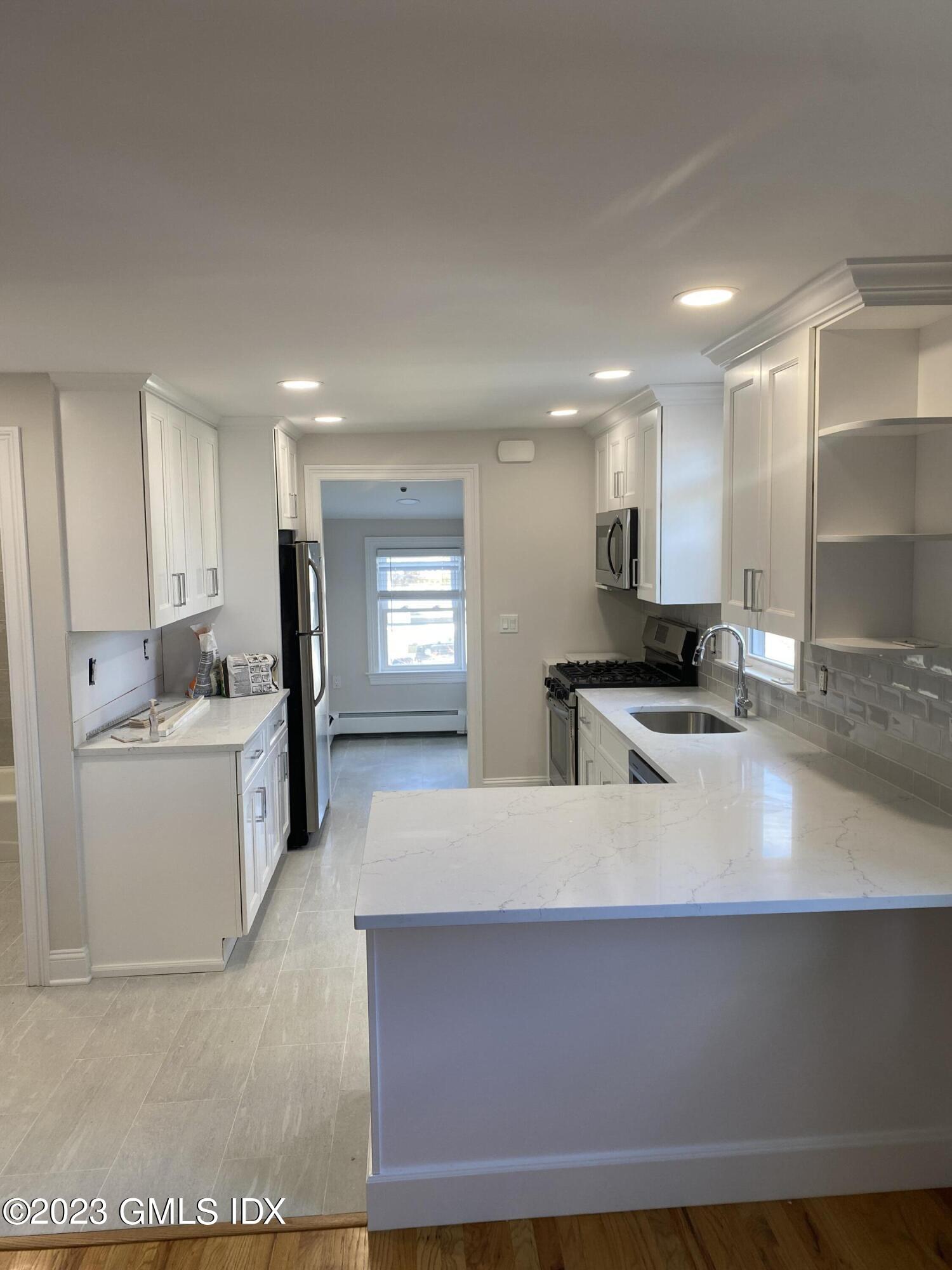 11 Old Field Point Road, Unit 2A Greenwich, CT 06830 - Photo 5 of 12 a large kitchen with kitchen island a sink stainless steel appliances and cabinets