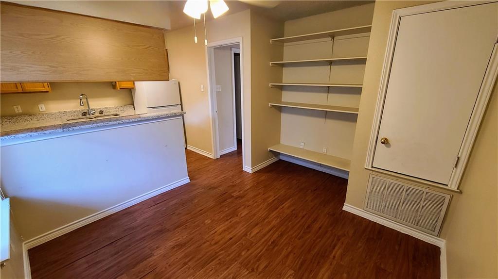 Kitchen featuring dark wood-style floors, white fridge, a ceiling fan, and brown cabinetry