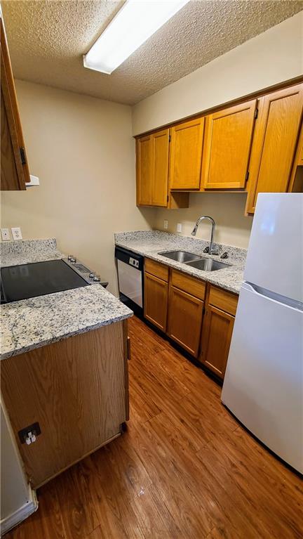 1907 Robbins Place, Unit 201 Austin, TX 78705 - Photo 2 of 5 Kitchen featuring freestanding refrigerator, brown cabinets, dark wood-style flooring, and a textured ceiling