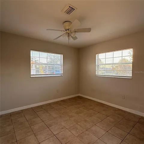 a view of an empty room and chandelier fan